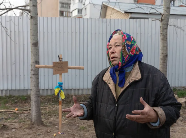 BuCHA, UKRAINE - Nisan. 06, 2022: Yakınlarının mezarının yakınında yaşayan bir kadın. 