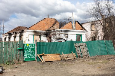ANDRIIVKA, UKRAINE - Nisan. 12, 2022: Rus işgalcilerin saldırısı sonucu Andriivka sokaklarında kaos ve yıkım yaşandı. Kapıdaki yazıt... İnsanlar yaşıyor, çocuklar.