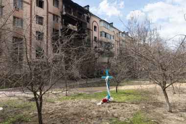 BuCHA, UKRAINE - Nisan. 12, 2022: Ukrayna 'nın Kyiv kenti yakınlarındaki Bucha şehri tarafından ele geçirilen apartman bloklarının yanındaki cesetlerle birlikte mezarlar.