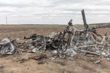 MAKARIV, UKRAINE - Nisan. 23, 2022: Makariv köyü yakınlarındaki bir tarlanın ortasında düşmüş ve yanmış bir helikopterin enkazı arasında ölen Rus askeri pilotların iskeletleri