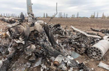 MAKARIV, UKRAINE - Nisan. 23, 2022: Makariv köyü yakınlarındaki bir tarlanın ortasında düşmüş ve yanmış bir helikopterin enkazı arasında ölen Rus askeri pilotların iskeletleri