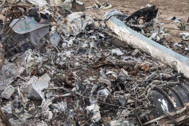 MAKARIV, UKRAINE - Nisan. 23, 2022: Makariv köyü yakınlarındaki bir tarlanın ortasında düşmüş ve yanmış bir helikopterin enkazı arasında ölen Rus askeri pilotların iskeletleri