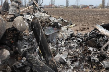 MAKARIV, UKRAINE - Nisan. 23, 2022: Makariv köyü yakınlarındaki bir tarlanın ortasında düşmüş ve yanmış bir helikopterin enkazı arasında ölen Rus askeri pilotların iskeletleri