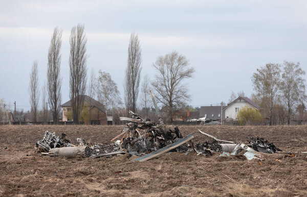 MAKARIV, UKRAINE - Apr. 23, 2022: Wreckage of a downed and burnt military helicopter in the middle of a field near the village of Makariv