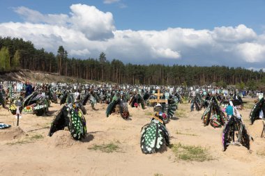 IRPIN, UKRAINE - Mayıs. 01, 2022: Irpin 'deki mezarlıkta çok sayıda taze mezar. İnsanlar sevdiklerini mezarlıkta anarlar.