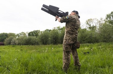 KYIV, UKRAINE - 14 Mayıs 2022: Bir asker, Ukrayna 'nın başkenti Kyiv' in sunumu kapsamında Toronto, Kanada 'daki bir yardım konseri sırasında toplanan bir insansız hava aracı tüfeği satın aldı.