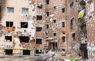IRPIN, UKRAINE - Mayıs. 13, 2022: Ukrayna 'ya karşı Rusya Savaşı. Irpin 'deki Rus istilacılar tarafından hasar görmüş bir yerleşim yeri. Yıkılmış bir evin penceresinde Ukrayna bayrağı.