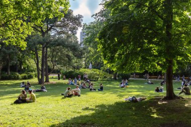 VIENNA, AUSTRIA - 26 Mayıs 2022: Gençler güneşli bir günde halk parkında dinleniyorlar. Şehir merkezindeki parkta dinlenen insanlar..