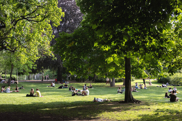 VIENNA, AUSTRIA - May 26, 2022: Young people are relaxing in popular public park on sunny day. People relaxing in a park in the city center.