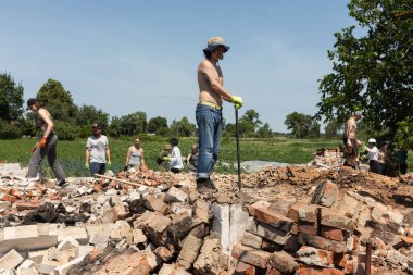 CHERNIHIV REG, UKRAINE - Jun. 19, 2022: Ukrayna 'da savaş. Bir grup yerel vatandaş, Rus savaş suçlularının saldırısı sonucu yıkılmış evlerin yıkıntılarını temizliyor.