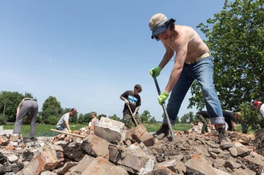 CHERNIHIV REG, UKRAINE - Jun. 19, 2022: Ukrayna 'da savaş. Bir grup yerel vatandaş, Rus savaş suçlularının saldırısı sonucu yıkılmış evlerin yıkıntılarını temizliyor.
