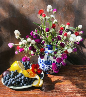 Romantik çiçek buketleri. Ev dekorasyonu ve çiçek düzenlemesi. Kompozisyonda gomphrena, nasturtium, üzüm ve limon kullanılır.