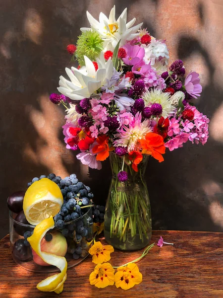 Romantic bouquets of flowers. Home decor and flowers arranging. In composition used dahlias, phlox, nasturtium, gomphrena, eucomis, grapes and lemon