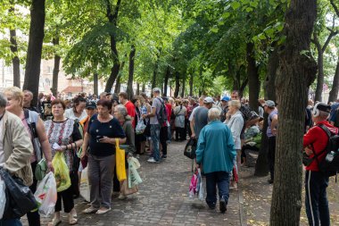 KHARKIV, UKRAINE - Aug. 02, 2022: A queue of people in need of humanitarian assistance. Volunteer organization Caritas Ukraine  distributes food to the needy in Kharkiv
