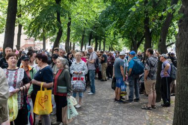 KHARKIV, UKRAINE - Aug. 02, 2022: A queue of people in need of humanitarian assistance. Volunteer organization Caritas Ukraine  distributes food to the needy in Kharkiv