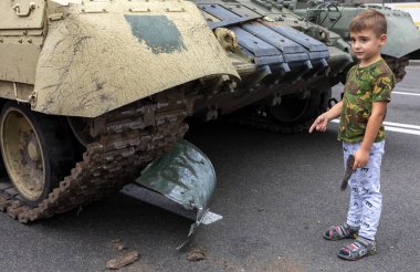 KYIV, UKRAINE - Aug. 20, 2022: Boy with toy gun near russian armoured military vehicles destroyed in fights with the Ukrainian army