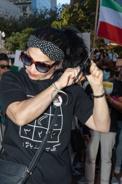 PORTLAND, OREGON, ABD - 15 Ekim 2022: İnsanlar İranlı kadınlarla dayanışma ve İran polisi tarafından öldürülen Mahsa Amini 'nin anısına düzenlenen bir gösteriye katılıyor. Saçını kesen bir kadın..