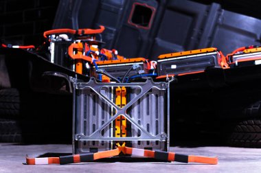 Electric car lithium power cell with power connections in front of maintained car battery. Blue toned. EV car battery at maintenance