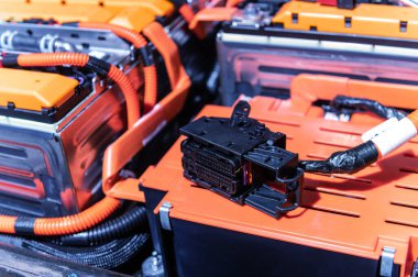 Electric car battery with power connections closeup. Blue toned. EV car battery at maintenance. High voltage power connector closeup