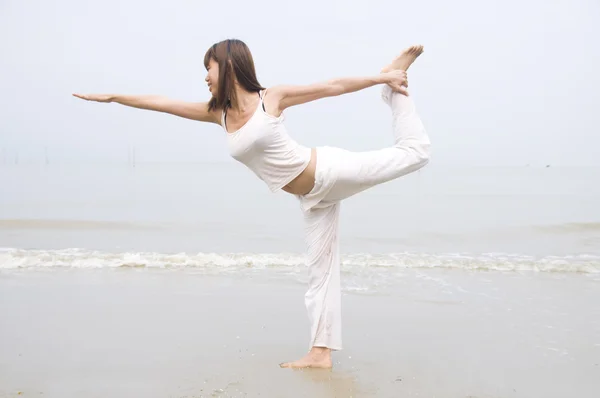 Ragazza asiatica che esegue yoga su una spiaggia — Foto Stock