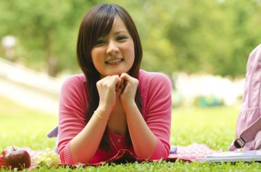 A shot of an asian student studying on campus lawn