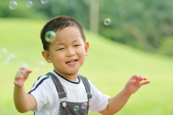 Felice ragazzo asiatico giocare sapone bolla, candido — Foto Stock