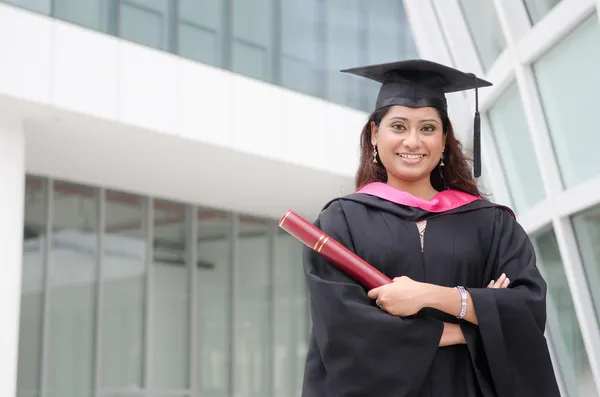 Jonge Indiase vrouwelijke afgestudeerd met campus achtergrond — Stockfoto