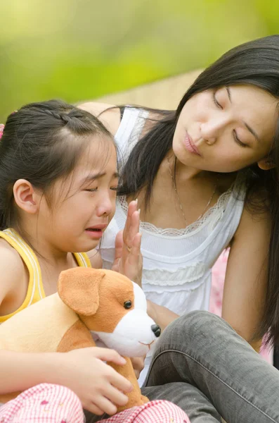 Menina chinesa asiática chorando enquanto sendo conforto por sua mãe, fundo ao ar livre — Fotografia de Stock