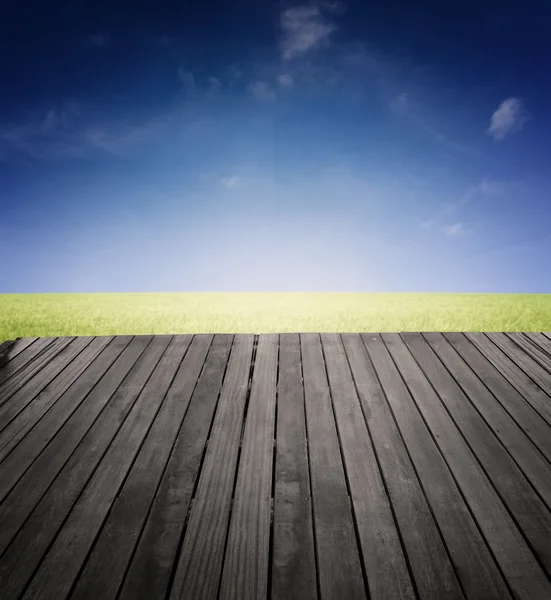 Wide vintage wood platform on the edge of green grassland — Stock Photo, Image