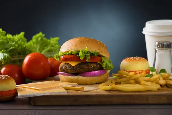 Hamburger Fast Food mit reichlich Rohstoffen im Hintergrund — Stockfoto