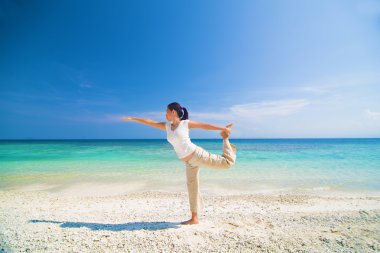 olgunlaşmış bir Asyalı kadın tarafından gerçekleştirilen beach yoga