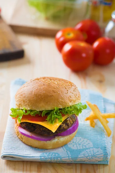 Hamburguesa con productos y materiales de comida rápida en el fondo — Foto de Stock