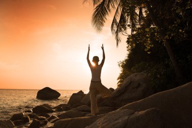 Kız siluet Yoga kumsalda güzel bir güneş sırasında gerçekleştiriliyor.