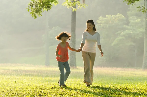 Asiática madre sosteniendo la mano de su hija caminando en el parque — Foto de Stock