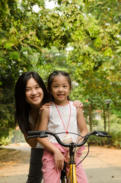 Asian chinese mother teaching her daughter riding bicycle outdoo — Stock Photo, Image