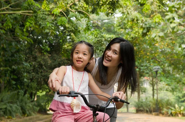 Asian chinese mother teaching her daughter riding bicycle outdoo — Stock Photo, Image