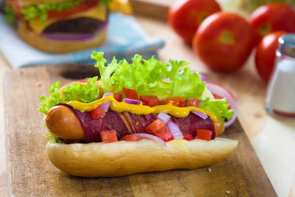 Hot dog and bacon served with mustard tomatoes and plenty of bac — Stock Photo, Image