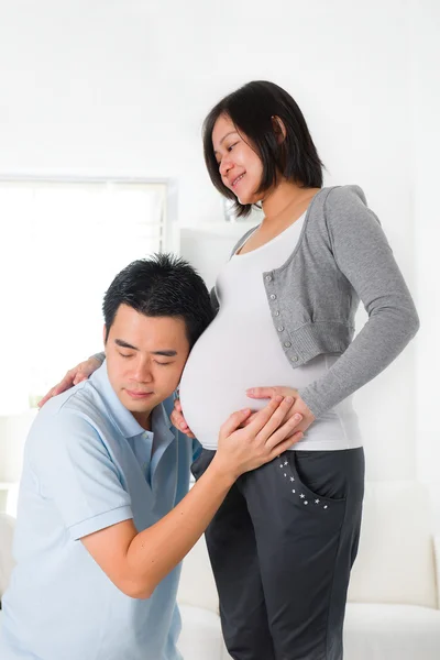 中国丈夫听着妻子的肚子 — 图库照片