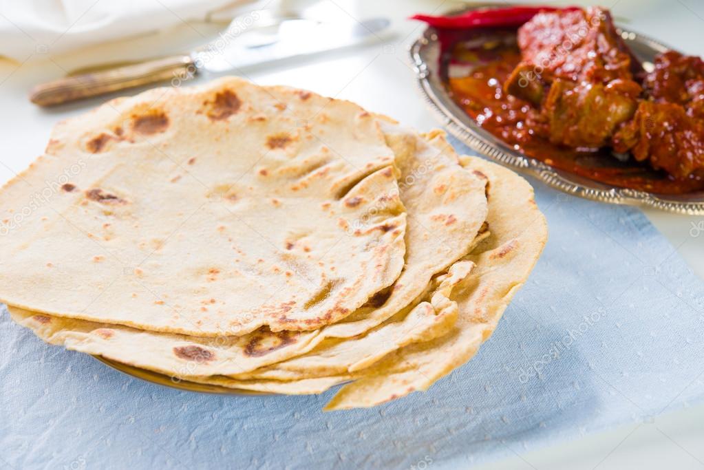 Chapatti roti and Indian food on dining table.
