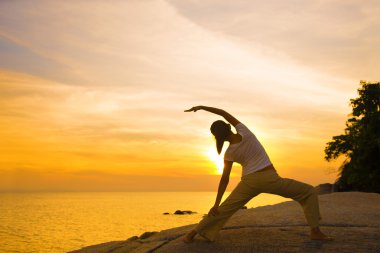 bir kız on sunset beach yoga yapmak silüeti