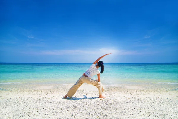 Aziatische vrouw yoga uitvoeren op een strand — Stockfoto