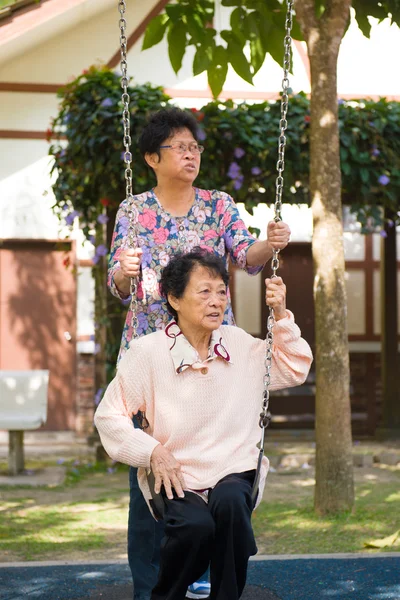 Asiatisk senior spiller swing i parken - Stock-foto