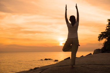 gün batımında sahilde Yoga uygulamak siluet genç erkek.