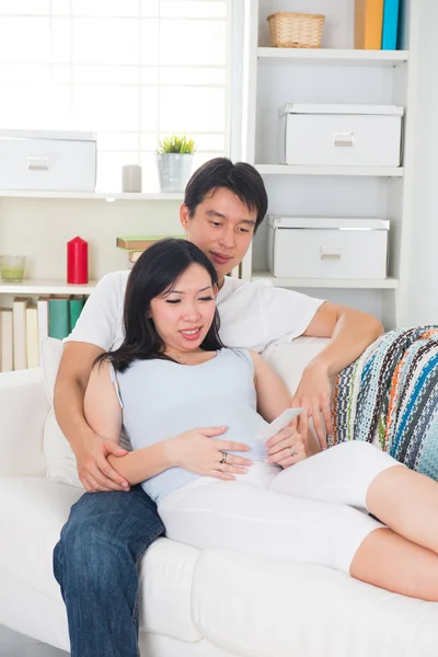 Aziatische zwangere man en vrouw kijken scan foto in livingroo — Stockfoto