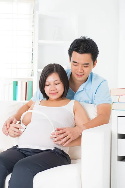 Chinesische schwangere Mutter und Vater mit Kopfhörer — Stockfoto