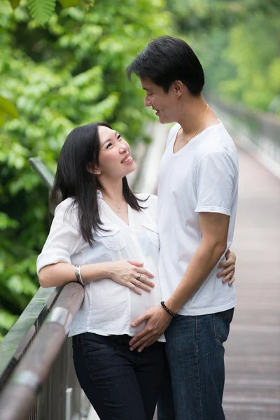 Gelukkige jonge zwangere Aziatische paar in de natuur — Stockfoto
