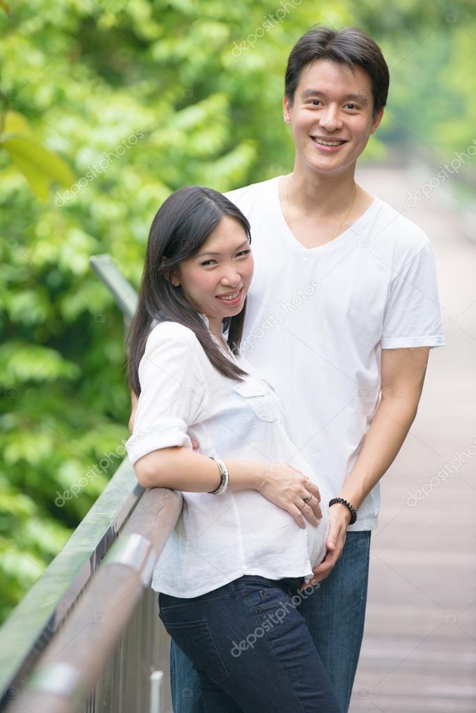 Happy young pregnant asian couple in the nature