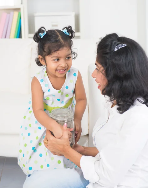 Indiska mor och dotter lägga mynt i flaska, spara pla — Stockfoto