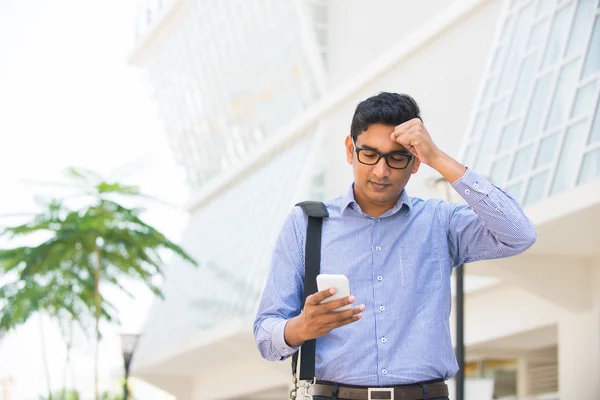 Verward kijken Indiase bedrijfsleven mannetje op een telefoon met office bac — Stockfoto