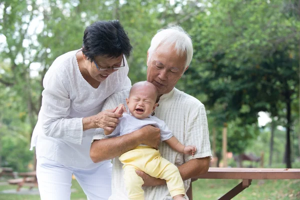 Asiatiske bedsteforældre trøstende grædende baby - Stock-foto